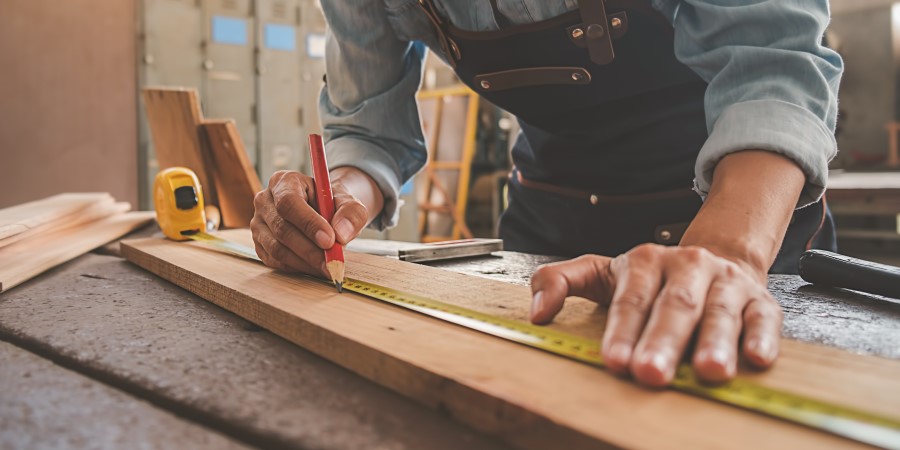 Carpenter measuring wood in shed
